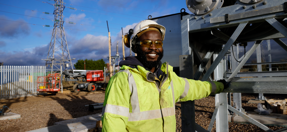 Image of a man in a high-vis jacket and hard hat smiling, looking at the camera
