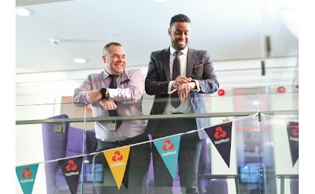 Two people smiling over a balcony in a NatWest building