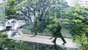 Person walking between buildings on floating platform, surrounded by glass reflections of verdant trees 
