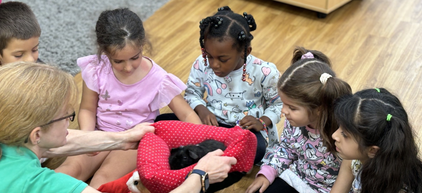 Six children and one teacher, sitting on a wooden floor, at Shining Stars Nursery