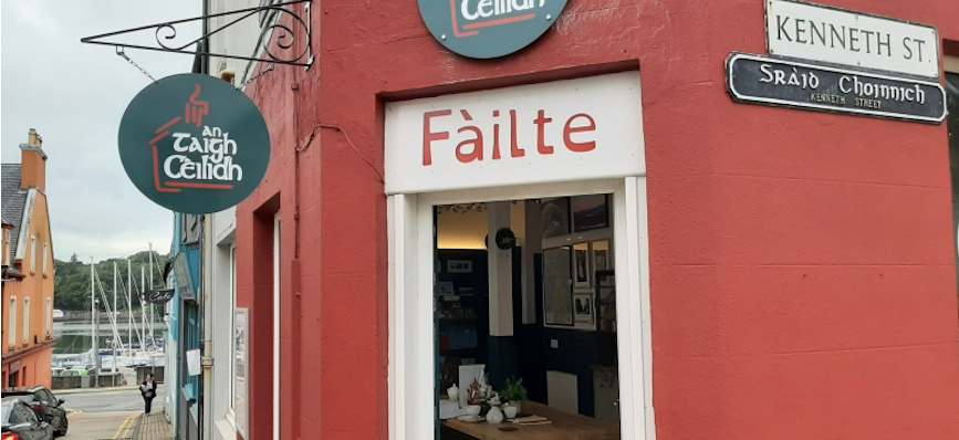 the front door of An Taigh Cèilidh, showing a red/orange building and ‘failte’ written in the door