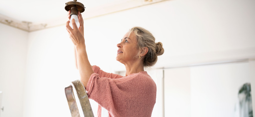 Lady on ladder changing lightbulb