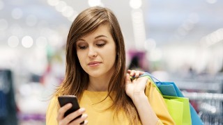 Person with shopping bags looking at a smartphone