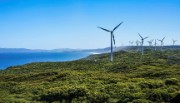 Wind turbines atop a verdant cliff under blue skies