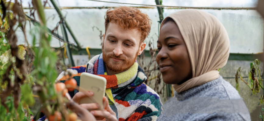 Two people looking at a phone inside a greenhouse