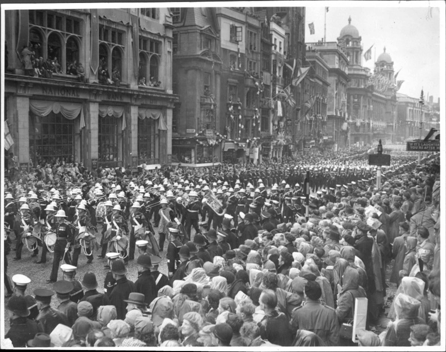Black and white image of marching band passing through crowds
