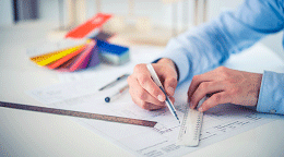 Person drawing a schematic with pen and ruler