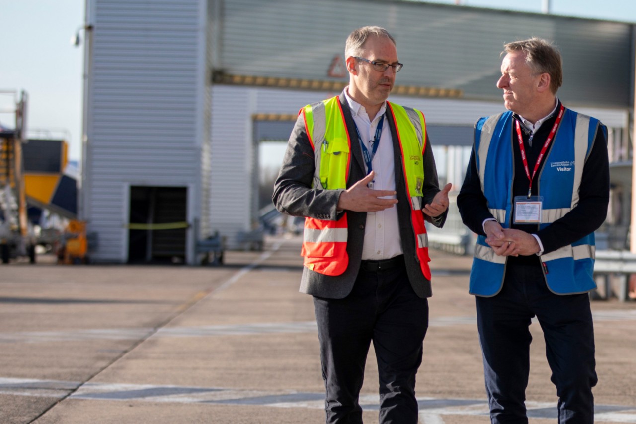 This image shows two men walking. They are both wearing high visibility jackets.