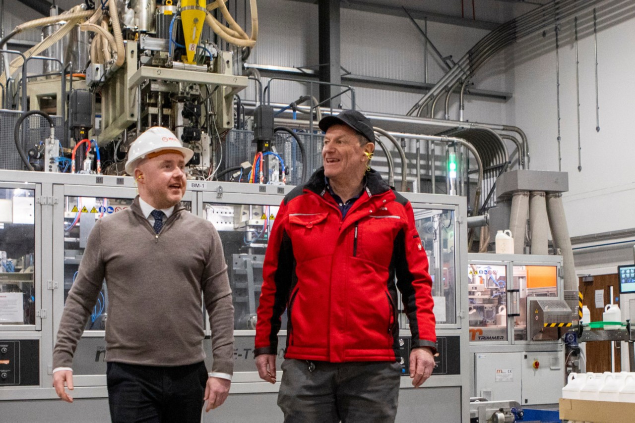 this images shows two men walking across a factory floor 
