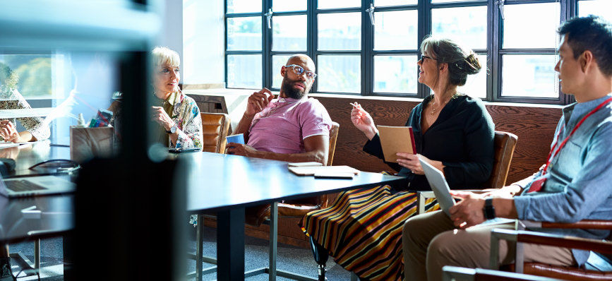This image shows men and woman together sat around a table. 