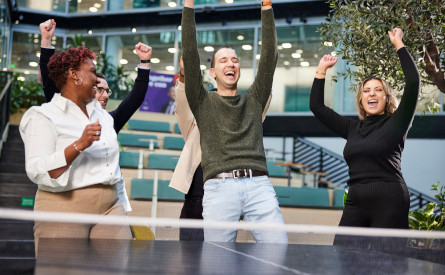 Colleagues celebrating while playing table tennis